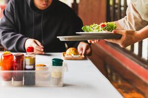 Waitress serving healthy green vegetable salad with bread bun in the morning. photo