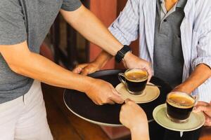 Senior man serving coffee with help of customer at cafe. photo