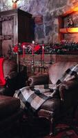 Empty comfortable living-room with Christmas decorations. Warm blankets on soft armchairs and candlesticks with red candles in the house. Vertical video