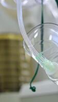 Breathing transparent oxygen mask hanging in the surgery room. Low angle view. Artificial lung ventilation machine working at backdrop. Vertical video