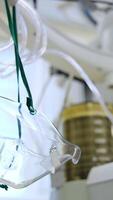 Oxygen mask hanging near the air pumping machine. Pulmoflator moving slowly at backdrop. Low angle view. Blurred background. Vertical video