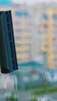 Cleaning dirty window with solution. Worker using household brush to wash window with special liquid inside. Blurred multi-storey building backdrop. Vertical video