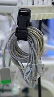 Folded wires from medical equipment and stethoscope hanging in the surgical room. Air pumping machine working at backdrop in blur. Vertical video
