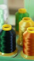 Bright threads in spools for tailor. Colorful spools with threads for sewing industry. Different colors of threads on the table. Handicraft. Vertical video