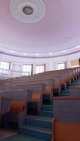Educational hall with nobody. Empty auditorium with wooden desks. Modern large meeting room with rows of tables and stairs. Vertical video