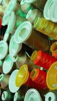 bobines de fil de différent couleurs sur le tableau. collection de coloré fils pour couture industrie. Contexte de beaucoup bobines avec coton chaîne. verticale video