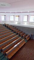Large empty lecture hall. Modern auditorium with seats for students in the university. Light educational room with a white board in the centre. Vertical video