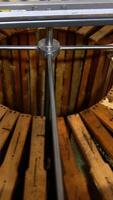 Electric metal barrel machine loaded with wooden frames. The equipment starts to rotate for getting fresh honey from honeycombs. Vertical video