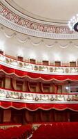 Rows of empty red velvet seats inside a theater or opera. No people in hall because of pandemic. Selective focus on opera interior. Vertical video