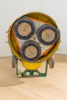 A yellow and green floor polishing machine on a light wooden floor, showing three circular polishing pads in a triangular arrangement. photo