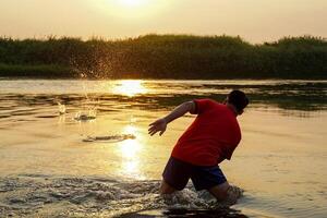Asian men play Stone skipping by throwing stones that bounce on the surface of the water, creating ripples on the water surface around the stones that gradually widen into ripples. photo