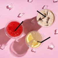 Three takeaway glasses of summer drinks with ice. Lemonade on colored background photo