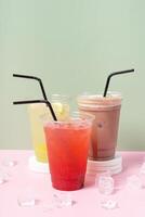 Three takeaway cups of summer drinks with ice. Lemonade on colored background photo
