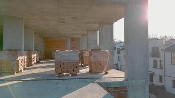 Sunlit construction site with unfinished brick and concrete building, Unfinished building structure with sunlight streaming through concrete pillars. video