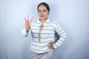 Beautiful asian young woman wearing sweater showing fingers number three while smiling confident photo