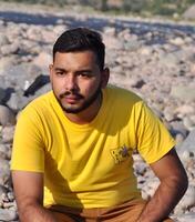 Handsome man with a stylish beard in a yellow t-shirt standing against a blurred mountain river background photo