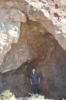 Boy exploring a mysterious cave on a remote island with dramatic natural rock formations photo