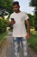 Young handsome Indian man using his mobile smartphone while sitting outdoors in a peaceful park setting photo