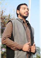 Portrait of a handsome young man standing in a lush park, enjoying the outdoor environment and natural light photo