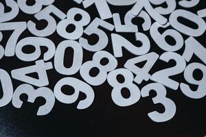 Numbers on black background. Numbers are scattered on the table. Black and white. photo