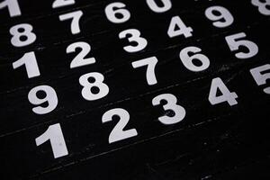 White numbers on a black background. Numbers scattered on the table. photo