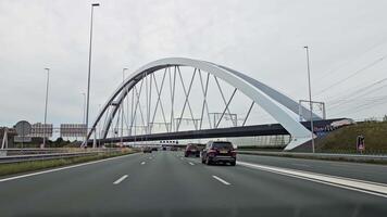 Amsterdam , Netherlands 11.10.2023 Modern arch bridge over Dutch highway with vehicles in motion, arch bridge spanning over a busy highway in the Netherlands with cars. video