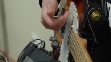 Close up view of a musician's hand skillfully tuning the strings of an electric guitar, getting ready for an upcoming music performance or an intense practice session video