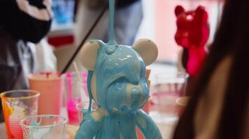During master class on making children's toys in the shape of bear, head of figurine is coated with epoxy paint, creating unique works of art and sculpture. video