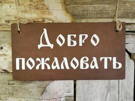 Welcome sign in Russian language hanging on rustic wooden wall, welcoming visitors to a cozy retreat photo