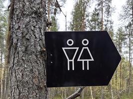 Sign indicating restroom facilities for men and women in a forested area. Comfortable environment in the park photo