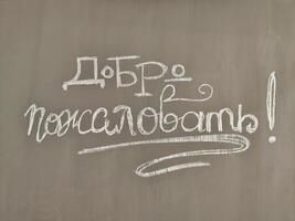 Joyful welcome message written in chalk on a classroom blackboard in Russian photo