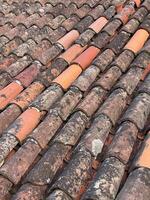 A detailed view of aged terracotta roof tiles in various earthy tones, featuring weathered textures and natural patterns. photo