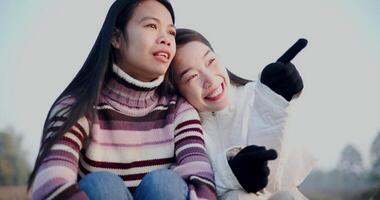 Handheld shot, Two Asian siblings sit and chat happily while watching the sunrise in the cold morning air. Winter Holiday video