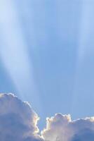 Background from blue sky with sun rays across clouds photo
