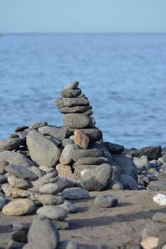 a stack of rocks on the beach near the ocean photo
