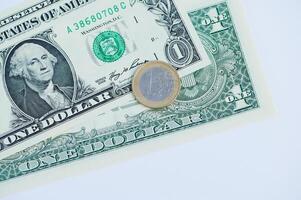 Closeup view of a euro coin resting on a one dollar bill displaying currency from different regions photo