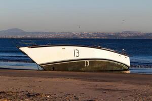 San Diego, CA, 2024 - Demasted Sailboat Aground On Sand Beach With Ocean photo
