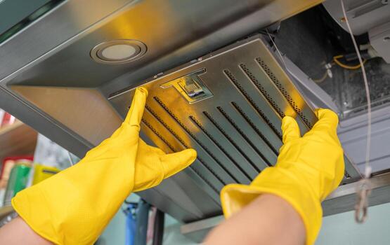 Housekeeping hands trying to removing a filters from cooker hood for cleaning it. Clean your filters every two to three months, depending on your cooking habits. photo