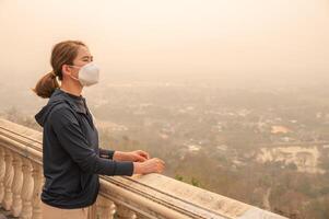 Asian woman while looking to Chiang Rai town covered with bad air pollution. PM2.5 levels meaning the air quality posed a health hazard. photo