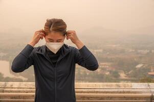 Asian woman wearing N95 mask for protect Bad air pollution PM2.5. PM2.5 levels meaning the air quality posed a health hazard. photo