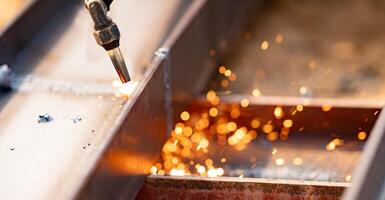 Skilled labor in metal fabrication. Use of torches for cutting metal. Safety measures and personal protective equipment for metalworkers. Precision and accuracy in metal cutting. photo