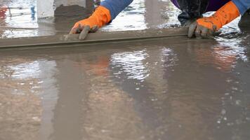 Mason worker working with trowel to level cement floor at construction site. A skilled construction worker spreading wet concrete to level wet concrete on a site floor. Foundation and flooring tasks. photo