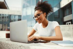 African American College Girl Using Laptop Learning Online And Browsing Internet Doing Homework In Modern University Outdoors. Student Typing On Computer, Studying Wearing Eyeglasses. Side View photo