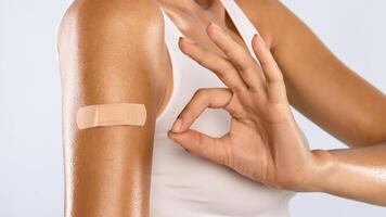 Successful Covid-19 Vaccination. Closeup Cropped View Of Vaccinated Woman Gesturing Okay Sign And Showing Arm With Adhesive Bandage After Getting Corona Virus Vaccine Injection, Isolated, Banner photo