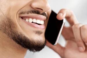 Phone Call. Closeup Shot Of Smiling Arab Man Talking On Cellphone, Unrecognizable Middle Eastern Guy Enjoying Mobile Communication, Having Pleasant Conversation, Selective Focus, Copy Space photo