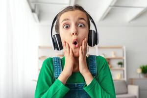 Wow. Portrait of young surprised girl looking at screen with open mouth in amazement, reading news having online call on laptop, touching cheeks in disbelief, web camera view photo