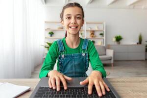 Doing Homework. Portrait of smiling student using laptop, studying online at home, happy girl typing on keyboard looking at pc screen, chatting with friends or making school research, web camera pov photo