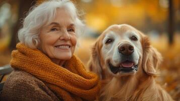 An elderly woman enjoys a warm afternoon in a park surrounded by autumn leaves, smiling joyfully next to her golden retriever, creating a heartwarming moment of companionship. photo