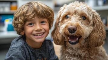 A cheerful young boy with curly hair sits closely next to a friendly dog, both radiating joy in an indoor setting filled with warm light and a sense of affection photo