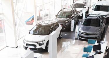 Top view of various newest modern sports, family, medium, multi purpose cars different colours and features at huge luxury dealership salon. Automobiles for sale, auto showroom, copy space photo